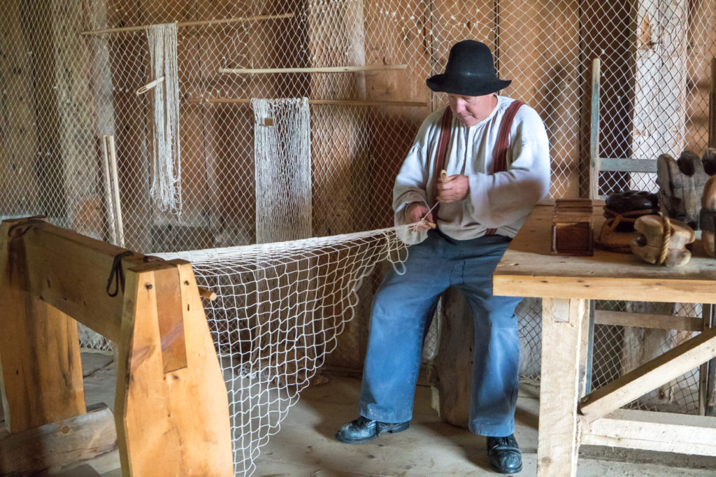 Artisan qui tresse des filets au Village Historique Acadien