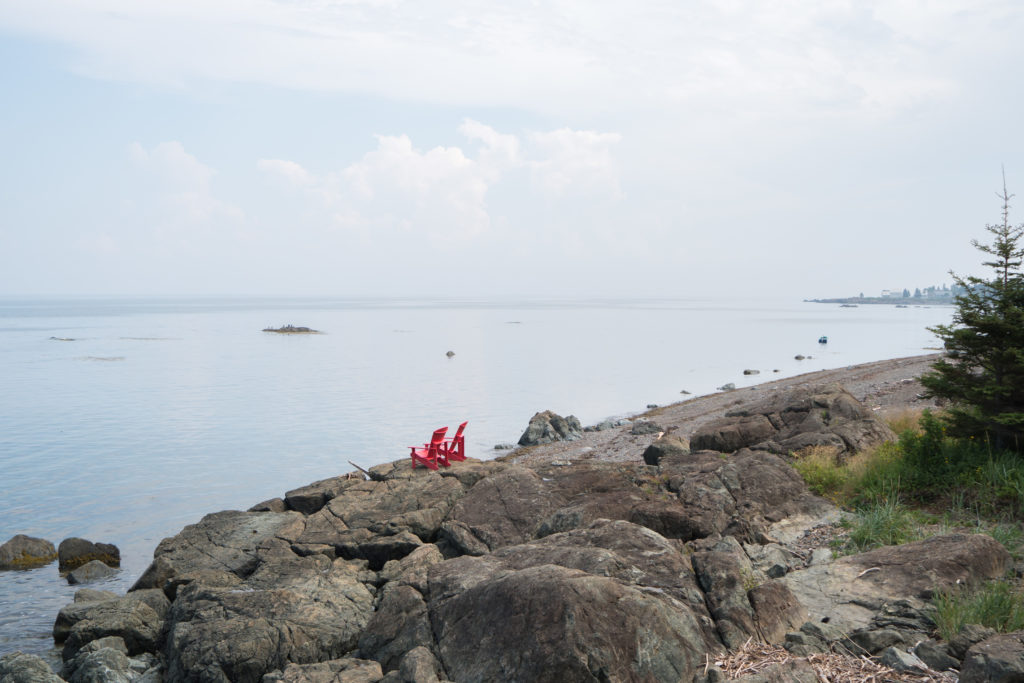 Le Camping au Rocher boisé - Chaises rouges devant la Baie des Chaleurs