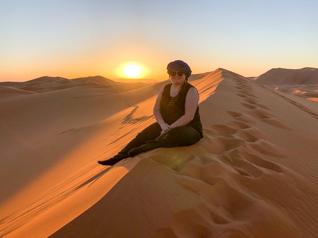 Jennifer assise sur une dune de sable dans le désert du Sahara près de Merzouga au Maroc