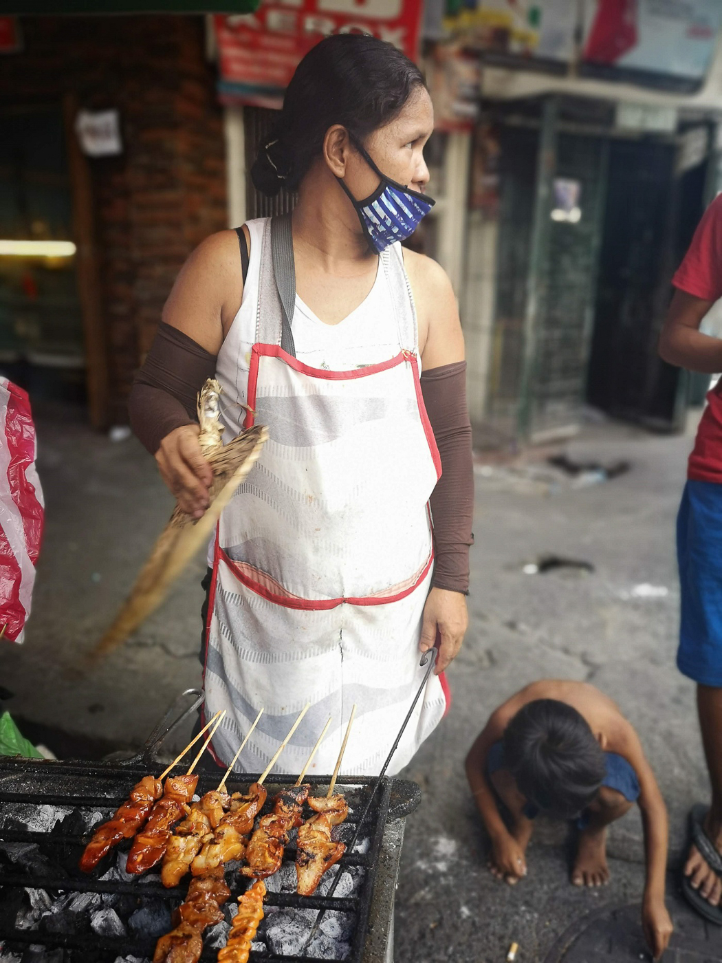 Femme grillant des brochettes philippines